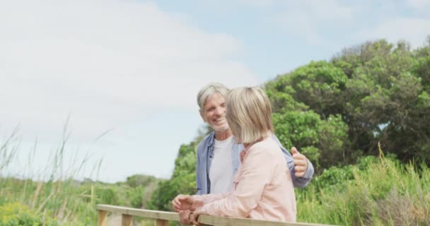 笑顔のシニア白人のカップルを受け入れ 屋外の橋の上に立っている 積極的な退職と健康的なアウトドアライフスタイル — ストック動画