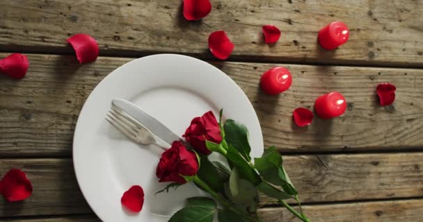 バレンタインの日に木製の背景にプレート上のキャンドルや赤いバラ バレンタインデー愛とお祝いのコンセプト — ストック動画
