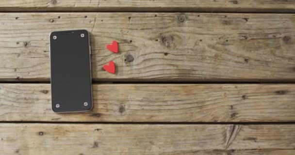 情人节时 木制的心和木制背景的智能手机 情人节 爱与庆祝的概念 — 图库视频影像