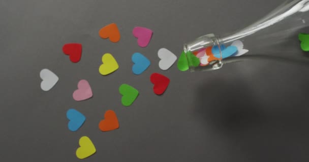 バレンタインデーの灰色の背景にカラフルな紙の心とボトル バレンタインデー愛とお祝いのコンセプト — ストック動画