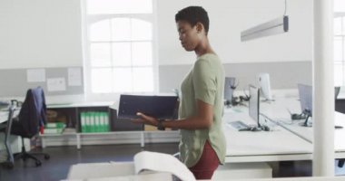 Afrika kökenli Amerikalı iş kadını ofiste dokümanlara bakıyor. Bağımsız yaratıcı iş, modern bir ofiste çalışmak..