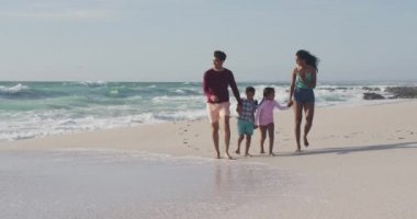 Mutlu İspanyol anne, baba, oğul ve kız el ele tutuşup sahilde yürüyor. Aile tatilleri, boş zaman ve birliktelik..