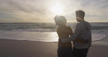 Gün batımında sahilde dikilen ve kucaklaşan romantik İspanyol çift. Tatiller, rahatlama, açık hava yaşam tarzı ve birliktelik..