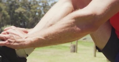Spor elbiseli, spor ayakkabı bağcıkları bağlayan, dışarıda güneşin altında spor yapmaya hazırlanan beyaz bir adam. Sağlıklı aktif yaşam tarzı, acemi birliğinde çapraz eğitim..