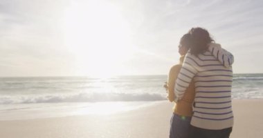 Mutlu İspanyol çiftin sahilde ayakta durup kucaklaşmasının arkası. Tatiller, rahatlama, açık hava yaşam tarzı ve birliktelik..