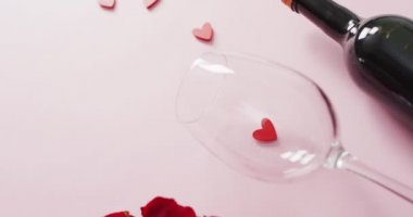 Sevgililer gününde pembe arka planda kırmızı güller ve şarap kadehleri. Sevgililer günü, aşk ve kutlama konsepti..