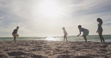 Mutlu İspanyol anne, baba, oğul ve kız sahilde top oynuyorlar. Aile tatilleri, boş zaman ve birliktelik..