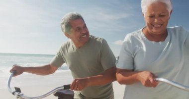 Mutlu İspanyol kıdemli çift gün batımında plajda bisikletle yürüyor. Sportif, sağlıklı ve aktif emeklilik yaşam tarzı.