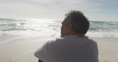 Gün batımında plajda oturan İspanyol son sınıf öğrencisinin arkası. Tatiller, tatiller, dinlenme ve emeklilik hayatı.