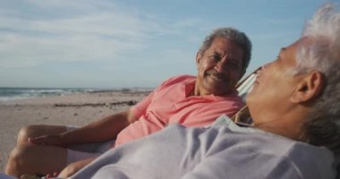 Mutlu İspanyol çift gün batımında plajda güneşleniyorlar. Aşk, romantizm ve aktif emeklilik yaşam tarzı.