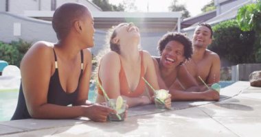 İçkileri yüzme havuzunda gülen çeşitli erkek ve kadın arkadaşlar grubu. Havuz partisinde arkadaşlarıyla takılıyor..