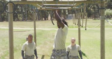 Ordu engelli parkurunda trapez çubukları kullanan Afro-Amerikan erkek askerleri. Sağlıklı aktif yaşam tarzı, acemi birliğinde çapraz eğitim..