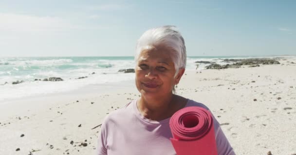 Portret Latynoskiej Starszej Kobiety Stojącej Plaży Trzymającej Matę Jogi Uśmiechającej — Wideo stockowe