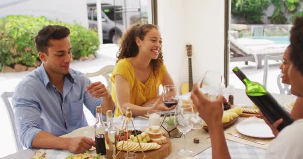 多様な男性と女性の友人のグループが一緒にパティオでのディナーパーティーで笑っています 自宅や庭で友達と遊ぶのは — ストック動画