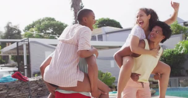 在泳池派对上 两个快乐而多样化的男性朋友在后院抱着负重的女性朋友 和朋友在家里和花园里玩 — 图库视频影像