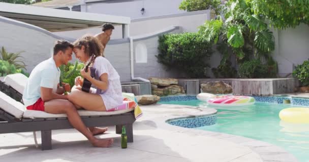 快乐的一对情侣在恋爱中弹吉他 他们的朋友在泳池派对上跳到游泳池里 和朋友在家里和花园里玩 — 图库视频影像
