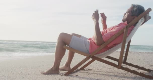 Λατίνος Ανώτερος Ισπανόφωνος Χαλαρώνοντας Στην Ξαπλώστρα Στην Παραλία Ηλιοβασίλεμα Χρησιμοποιώντας — Αρχείο Βίντεο