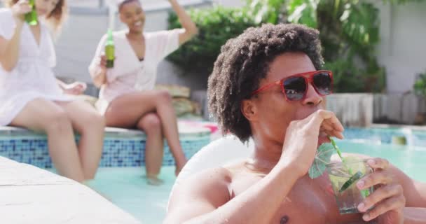 快乐的非洲裔美国人 戴着太阳镜 和朋友一起在游泳池里喝酒 和朋友在家里和花园里玩 — 图库视频影像