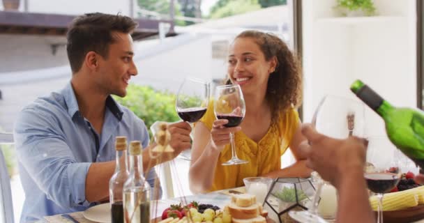 パティオでのディナーパーティーでは ワインで乾杯する2人の多様な男性と女性の友人 自宅や庭で友達と遊ぶのは — ストック動画