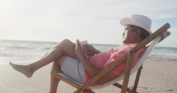 Latin Senior Hispanic Man Relaxing Sunbed Beach Sunset Reading Book — Αρχείο Βίντεο