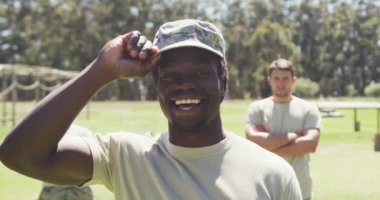 Engel parkurunda başlık takmış, arkasında başkaları ile birlikte gülümseyen Afrikalı Amerikalı erkek askerin portresi. Sağlıklı aktif yaşam tarzı, acemi birliğinde çapraz eğitim..