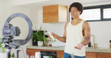 Afro-Amerikan bir adam yemek pişiriyor, smoothie hazırlıyor ve video çekiyor. sağlıklı aktif yaşam tarzı ve evdeki uygunluk.
