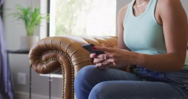 Kafkasyalı mutlu kadın evde vakit geçiriyor ve akıllı telefon kullanıyor. Teknoloji kullanarak evde vakit geçirmenin tadını çıkarıyorum..