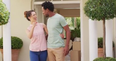 Yeni evin anahtarlarını elinde tutan ve neşeyle kucaklaşan mutlu çift. Yatırım ve yeni başlangıçlar, mülk ve ev sahipliği