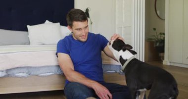 Kafkasyalı adam evde köpeğiyle oynuyor. Kaliteli boş vakitlerin tadını çıkarıyor..