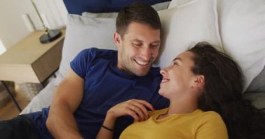 Kafkasyalı mutlu çift yatakta dinleniyor ve öpüşüyor. Kaliteli boş vakitlerin tadını çıkarıyor..