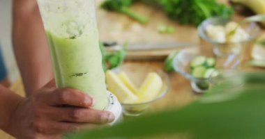 Afro-Amerikan erkeği sağlıklı yeşil smoothie hazırlıyor. sağlıklı aktif yaşam tarzı ve evdeki uygunluk.