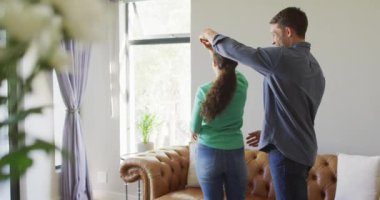 Genç, mutlu, beyaz bir çift evde konuşup dans ediyor. Kaliteli boş vakitlerin tadını çıkarıyor..