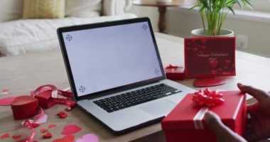 Çift ırklı bir adamın mevcut olduğu orta bölüm ve Valentine 'ın video görüşmesi dizüstü bilgisayarında. Sevgililer Günü kutlaması, romantizm ve iletişim teknolojisi.