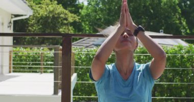 Terasta oturmuş meditasyon yapan rahat bir melez kadın. sağlıklı aktif yaşam tarzı ve kaliteli boş zaman harcamak.