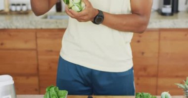 Afro-Amerikan erkeği sağlıklı yeşil smoothie hazırlıyor. sağlıklı aktif yaşam tarzı ve evdeki uygunluk.
