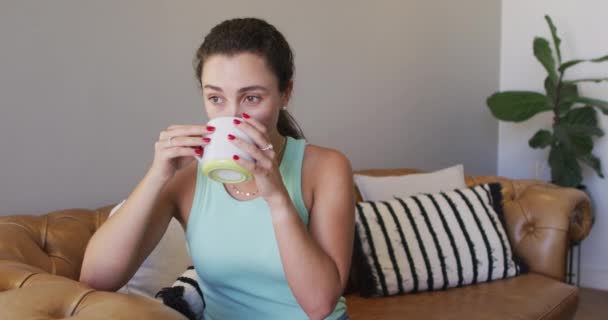 自宅でコーヒーを飲みながら座っている白人女性をリラックスさせます 自宅で質の高い余暇を楽しむ — ストック動画