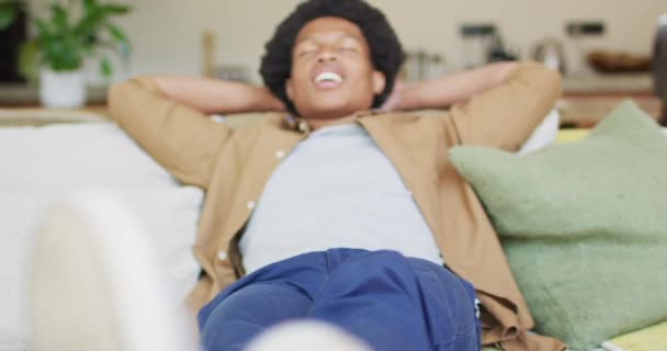 幸せなアフリカ系アメリカ人の男性は ソファの上に座って休んでリラックスした 余暇一人で家でリラックスして — ストック動画
