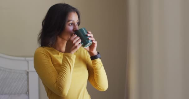 Relajada Mujer Birracial Bebiendo Café Mirando Por Ventana Pasar Tiempo — Vídeo de stock