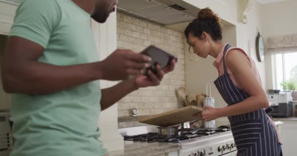 Mujer Biracial Feliz Poniendo Verduras Una Cacerola Hablando Con Pareja — Vídeo de stock