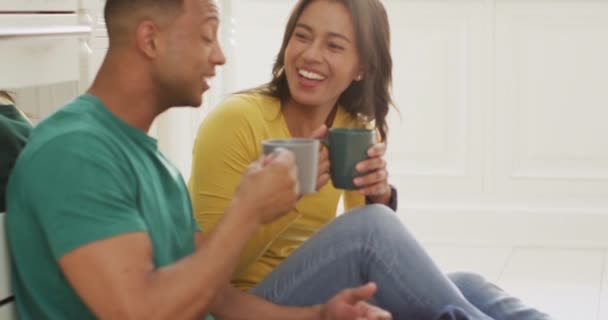 Feliz Pareja Birracial Sentada Piso Cocina Tomando Café Hablando Amor — Vídeo de stock