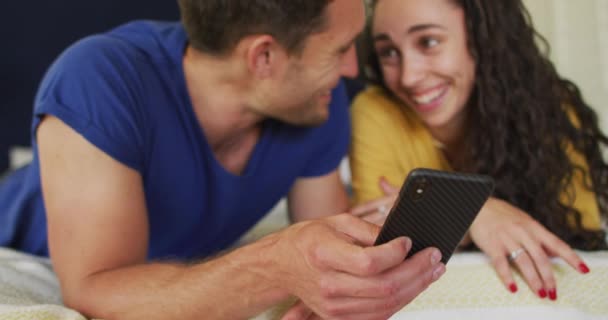 幸せな原因アジアのカップルベッドの上に横たわるとスマートフォンを使用しています テクノロジーを駆使して自宅で上質な余暇を楽しむ — ストック動画