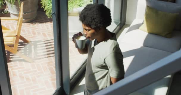 Αφροαμερικάνος Κοιτάζει Παράθυρο Και Πίνει Καφέ Στο Σπίτι Ελεύθερος Χρόνος — Αρχείο Βίντεο