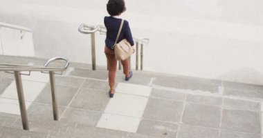 Afrika kökenli Amerikalı iş kadını akıllı telefondan konuşuyor. Dijital göçebe şehirde geziyor, dolaşıyor..