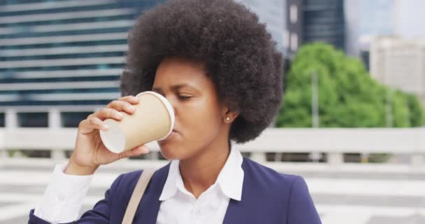アフリカ系アメリカ人の実業家が市内でテイクアウトコーヒーを飲んでいる 外にも街中にもデジタル ノマドが — ストック動画