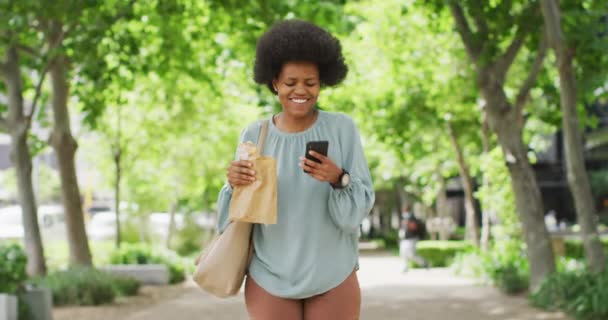 Αφροαμερικανή Επιχειρηματίας Τρώει Και Χρησιμοποιεί Smartphone Ψηφιακός Νομάδας Κινήσει Έξω — Αρχείο Βίντεο
