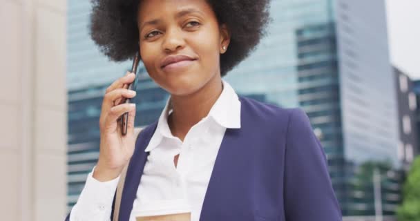 アフリカ系アメリカ人のビジネスマンがスマートフォンで話しているのを笑っている 外にも街中にもデジタル ノマドが — ストック動画