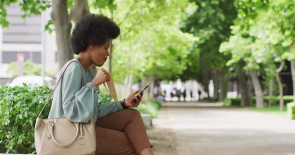 Αφροαμερικανή Επιχειρηματίας Τρώει Και Χρησιμοποιεί Smartphone Ψηφιακός Νομάδας Κινήσει Έξω — Αρχείο Βίντεο