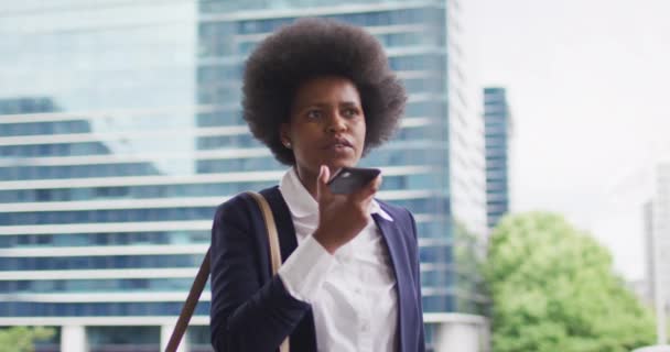 アフリカ系アメリカ人のビジネスマンがスマートフォンで話している 外にも街中にもデジタル ノマドが — ストック動画