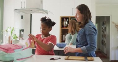Kafkasyalı mutlu kadın ve Afrikalı Amerikalı kızı birlikte yemek paketliyor. ev hayatı, evde zaman geçirmek..