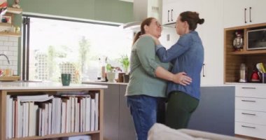 Mutfakta gülümseyen ve dans eden beyaz lezbiyen çift. Ev hayatı, evde dinlenerek boş zaman geçirmek..